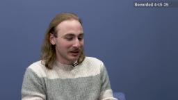 Evan Teplensky being interviewed with blue background. 