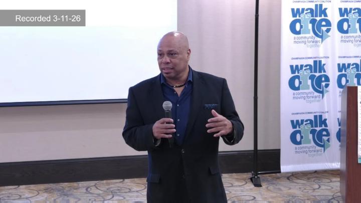 Tracy Parsons at front of room in front of Walk as One banner. 